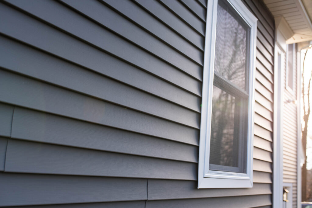 Side of residential home with dark gray vinyl siding | roloxhomeservicellc