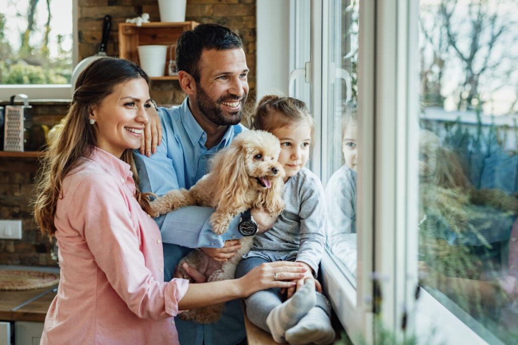 Happy family with child and dog looking out window | roloxhomeservicellc