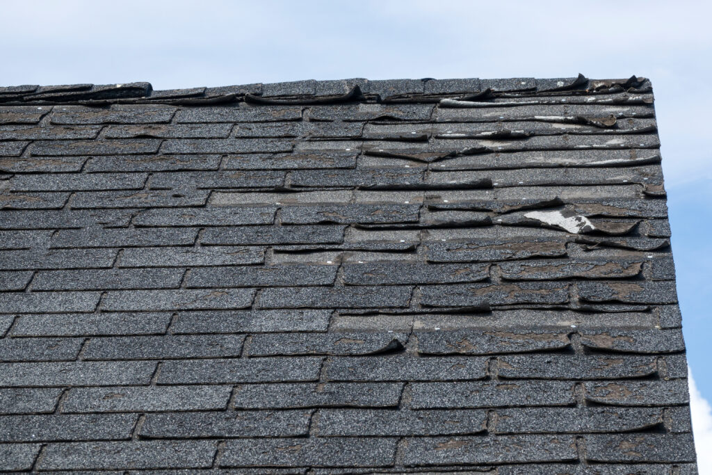 A section of a roof with missing and damaged shingles
