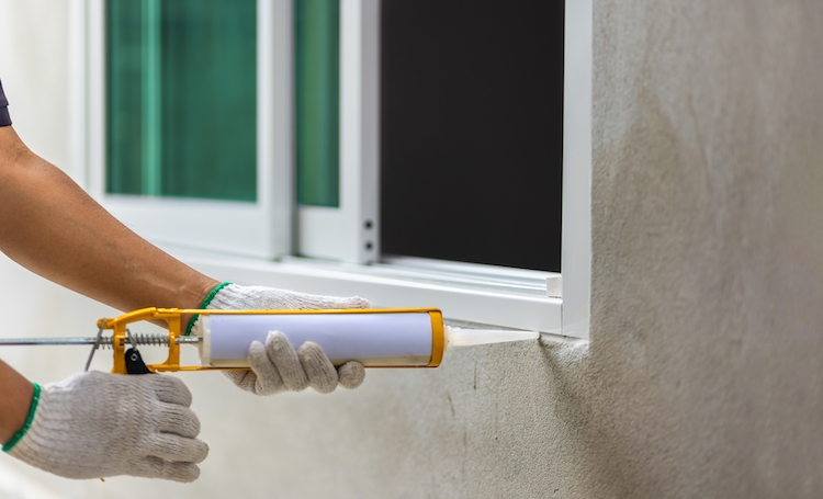 Worker caulking a window on residential home. | Rolox Home Service