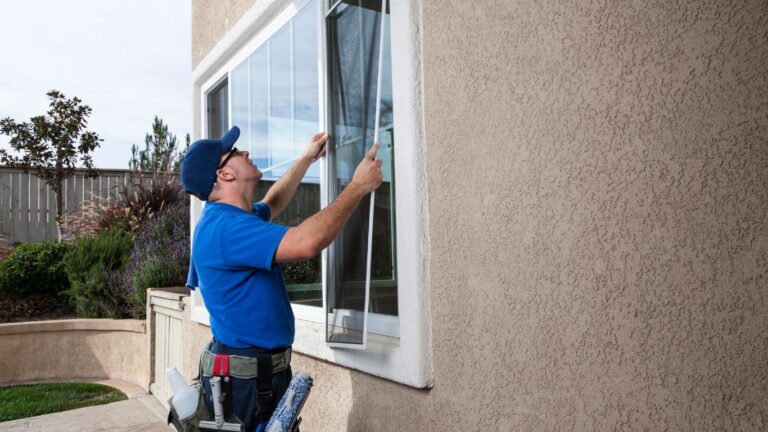 man in blue shirt hanging a screen over a window
